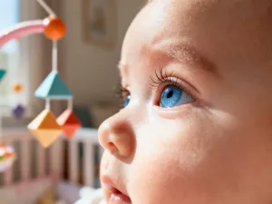 Pusty wózek głęboki z gondolą ustawiony w przytulnym, słonecznym pokoju dziecięcym.